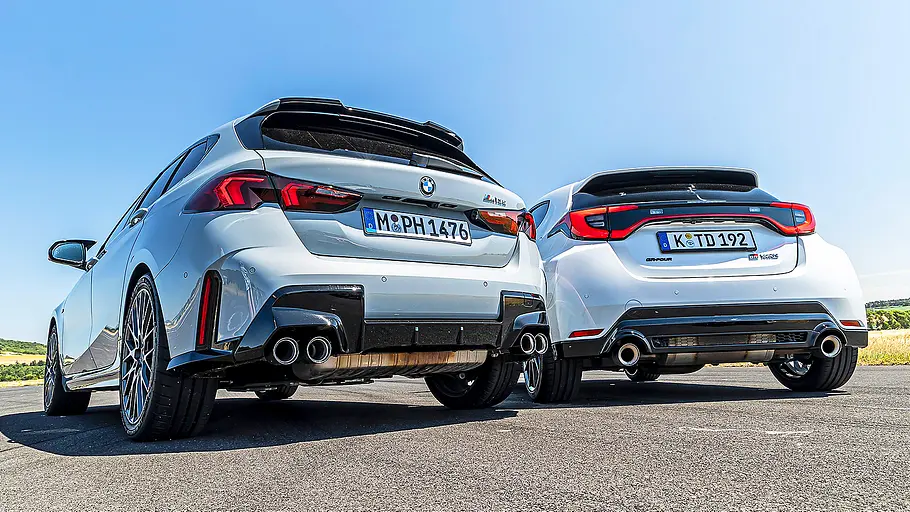 Blick von schräg hinten auf die beiden fahrenden Kompaktsportler BMW M135 und Toyota GR Yaris.