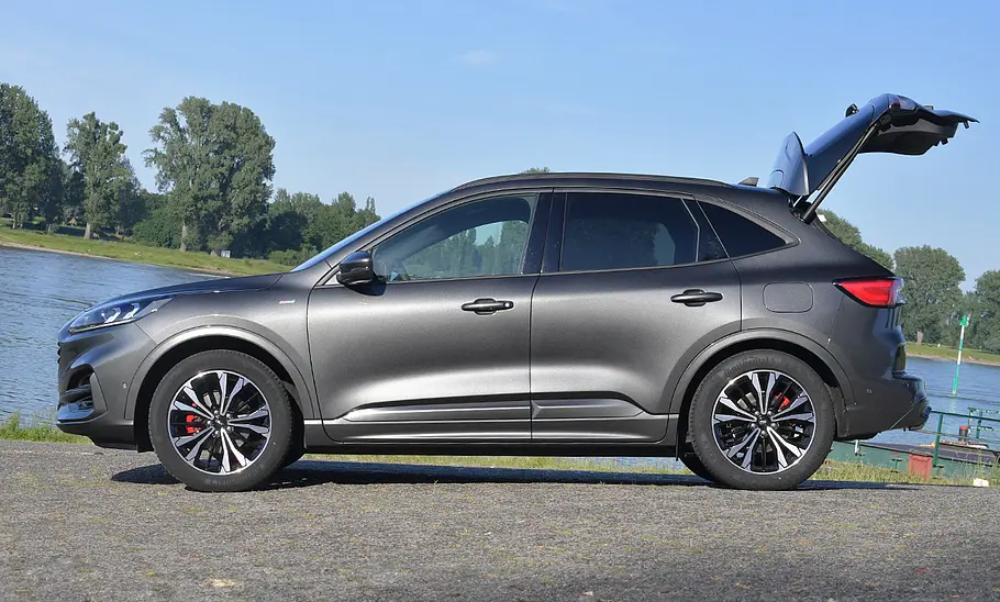 Ford Kuga (2019) Der Ford Kuga (2019) steht an einem Flussufer, mit geöffneter Heckklappe von links fotografiert.