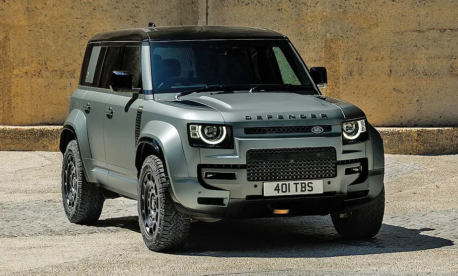 Land Rover Defender Octa (2024) steht vor einer Sandstein-Wand, Ansicht von vorne rechts.