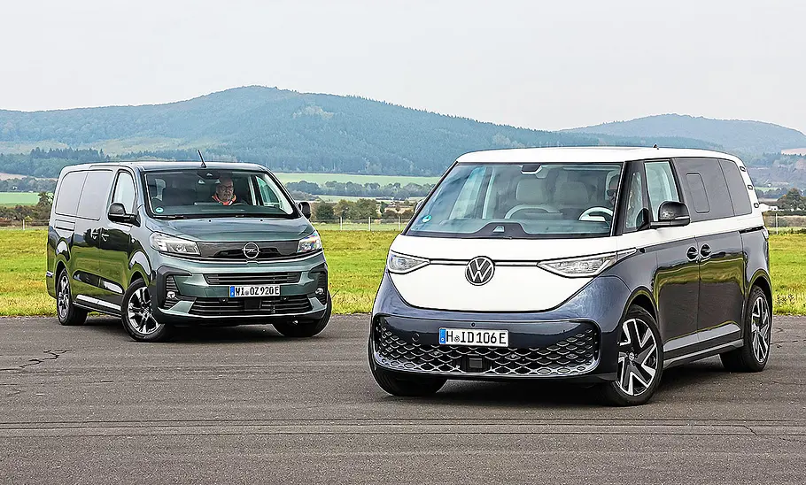 Gruppenbild mit Blick von schräg vorne auf die beiden Elektro-Vans Opel Zafira Electric und VW ID. Buzz.