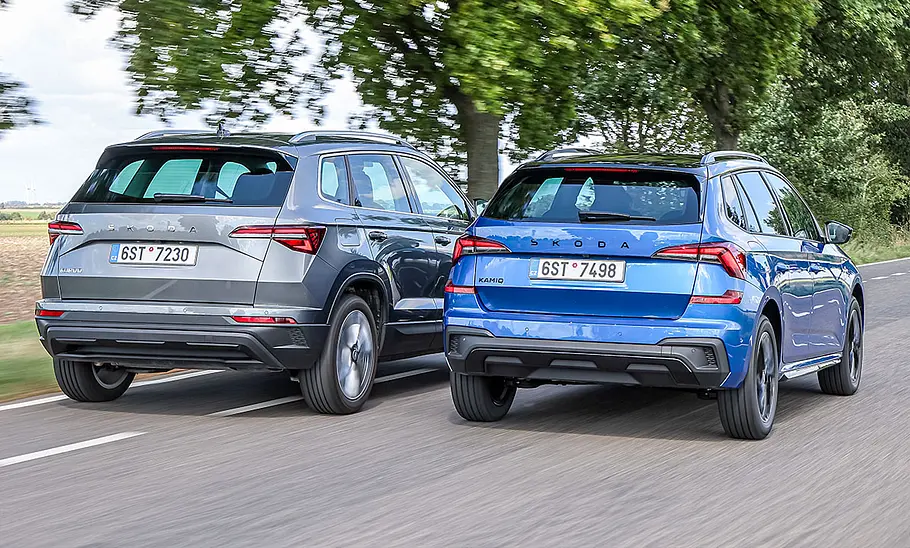 Skoda Karoq und Skoda Kamiq fahren nebeneinander auf einer Landstraße, von hinten fotografiert.