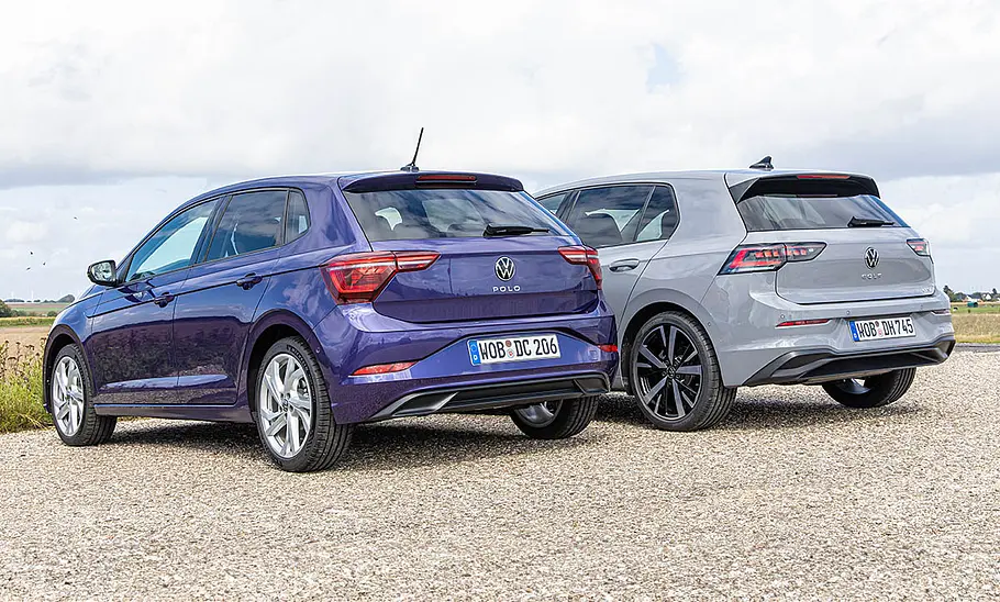 VW Polo und VW Golf stehen nebeneinander auf einem Schotterplatz, von hinten links fotografiert.