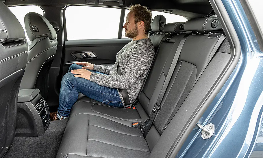 Eine Person sitzt auf der Rücksitzbank des BMW 3er Touring.
