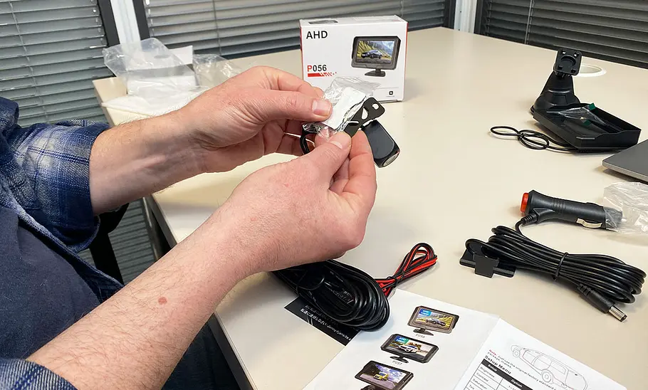 Tester beim Auspacken der Rückfahrkamera Vtopek AHD P056, fotografiert am Schreibtisch.