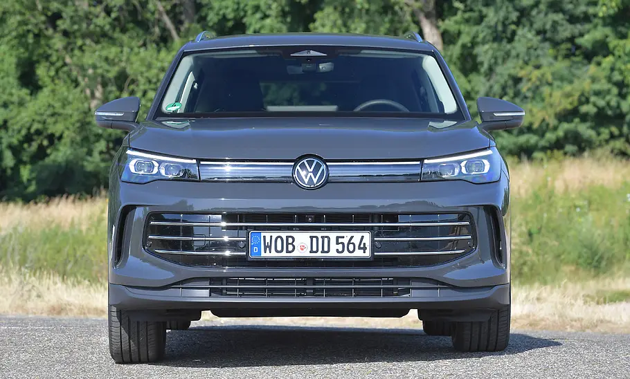 VW Tiguan Der VW Tiguan steht auf einem Parkplatz vor einer Wiese und Bäumen. Ansicht von vorne.