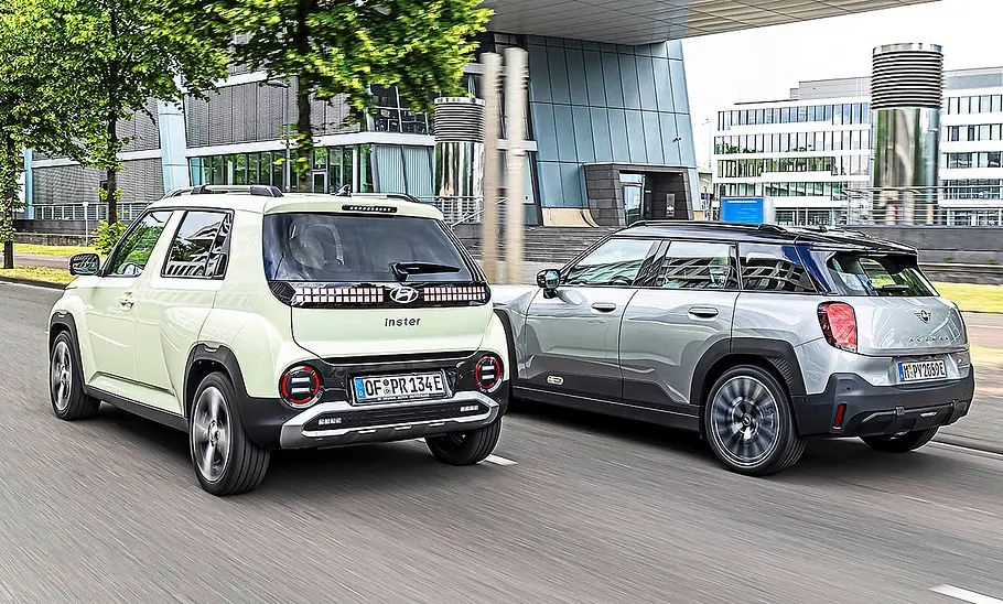 Blick von schräg hinten auf die fahrenden Elektro-Kleinwagen Hyundai Inster und Mini Aceman.