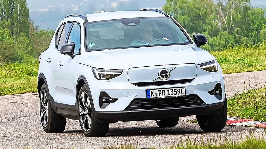 Blick von schräg vorne auf den fahrenden Volvo EX40, der zügig eine enge Kurve passiert.