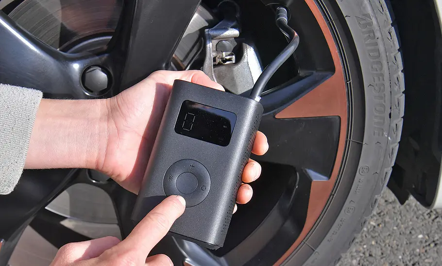 Testerhände mit Delgeo Mi Mijia, fotografiert von der Seite. Akku-Luftpumpe Delgeo Mi Mijia im Test