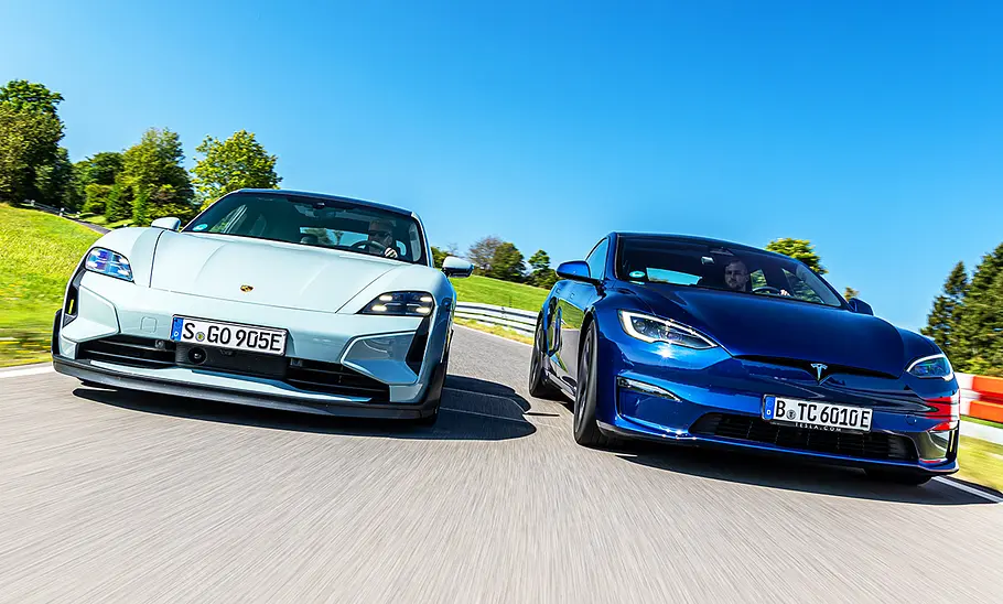 Der Porsche Taycan Turbo GT und das Tesla Model S Plaid auf der Landstraße, von schräg vorne fotografiert.