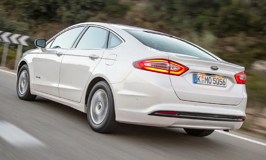 Ford Mondeo Hybrid (2015) Der Ford Mondeo Hybrid (2015) fährt auf einer Straße, von hinten links fotografiert.