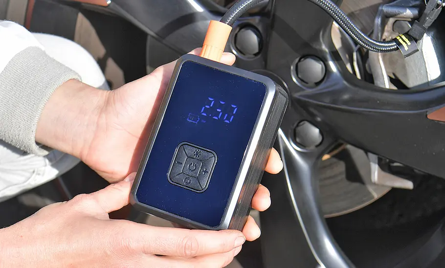 Testerhände mit Oasser LS4012 Tire Inflator, fotografiert von der Seite. Akku-Luftpumpe Oasser LS4012 Tire Inflator im Test