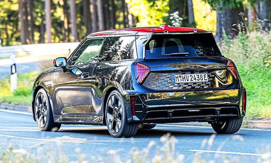 Blick von schräg hinten auf den fahrenden Mini Cooper JCW e.