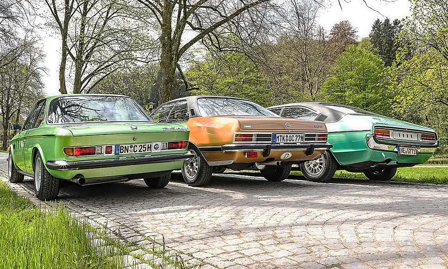 BMW 2.5 CS/Opel Commodore GS/E Coupé/Ford Granada 3.0 V6 Coupé parken nebeneinander auf einer Straße. Ansicht von hinten links.