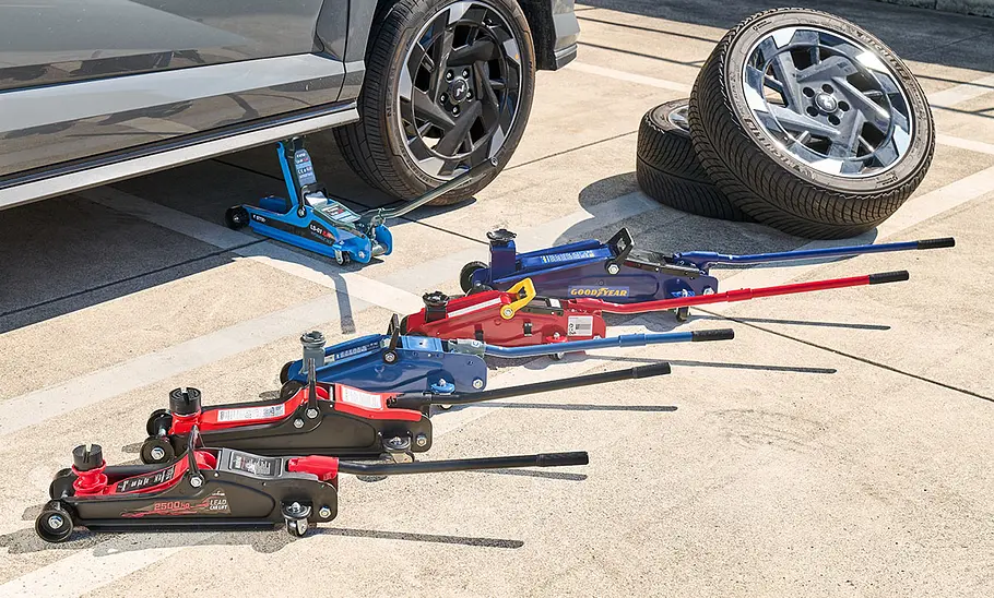 Sechs Rangierwagenheber im Test vor einem Hyundai Kona und einem Reifenstapel, fotografiert von oben.