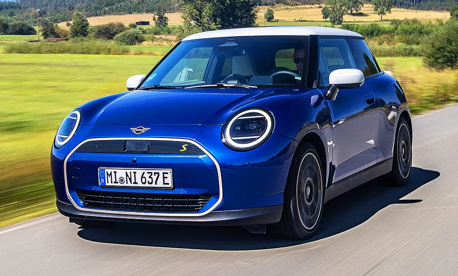 Der Mini Cooper SE auf der Landstraße, von schräg vorne fotografiert.