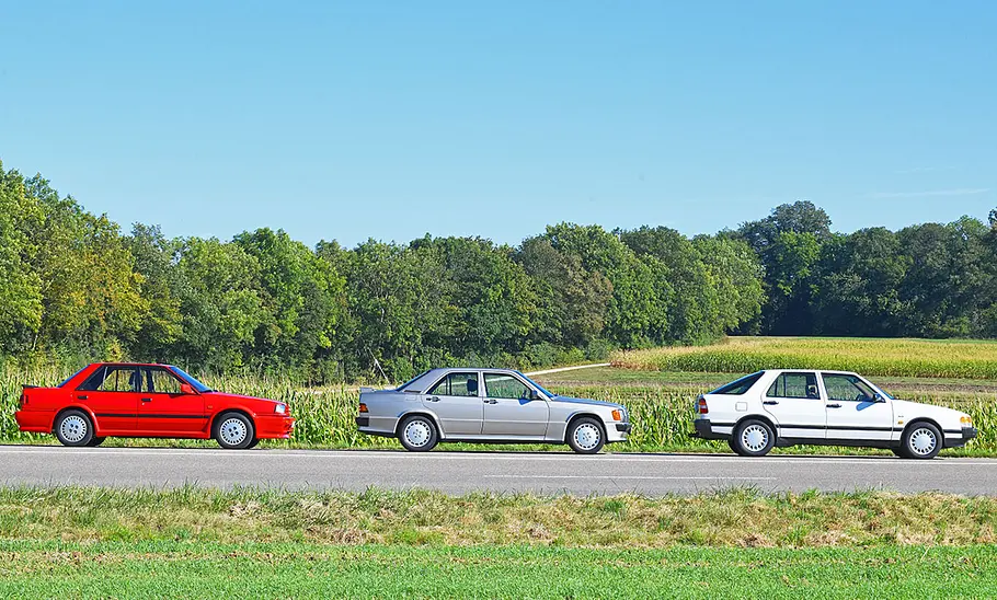Nissan Bluebird/Mercedes 190 E 2.5-16/Saab 9000 2.3i 16V Nissan Bluebird, Mercedes 190 E 2.5-16 und Saab 9000 2.3i 16V stehend von der Seite.
