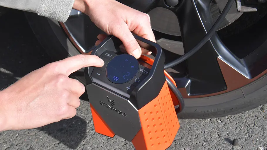 Display der Akku-Luftpumpe Etenwolf Zephyr S3 mit Testerhänden vor einem Rad, fotografiert von schräg oben.