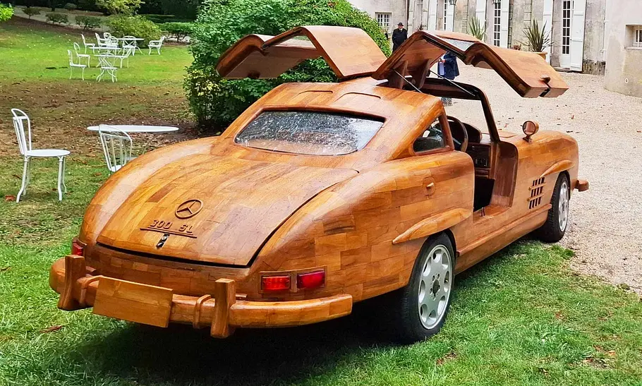 Mercedes Benz 300 SL aus Holz Der Mercedes Benz 300 SL aus Holz steht vor einer Burg und wurde von schräg hinten fotografiert.