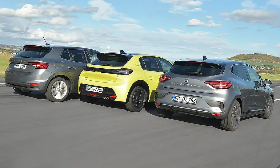 Skoda Fabia, Peugeot 208 Hybrid und Mitsubishi Colt Hybrid fahren nebeneinander auf einer Flugzeuglandebahn, von hinten rechts fotografiert.