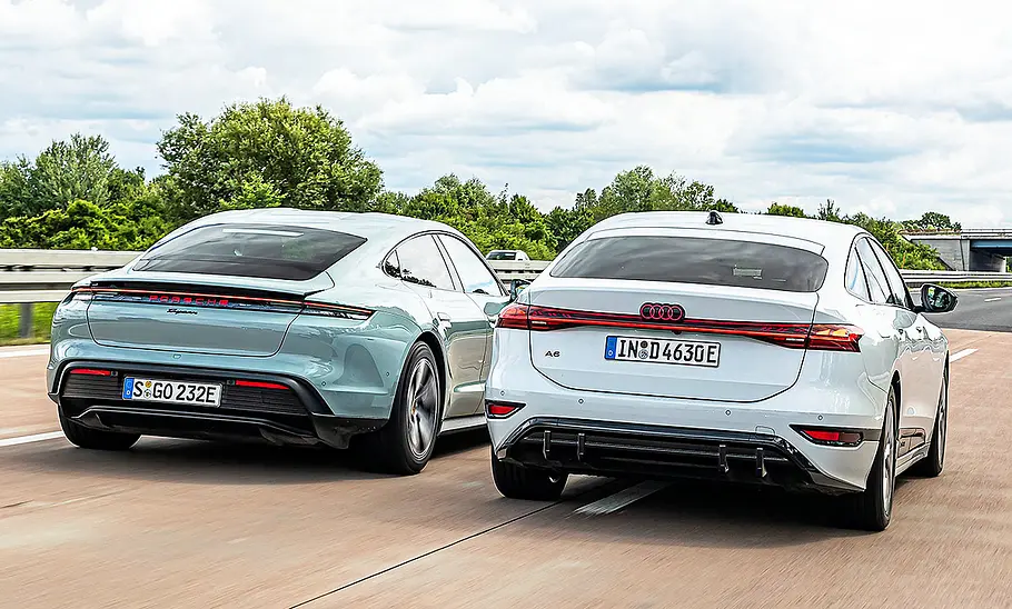 Blick von hinten auf die beiden Elektroautos Porsche Taycan und Audi A6 e-tron, die auf der Autobahn nebeneinander her fahren.