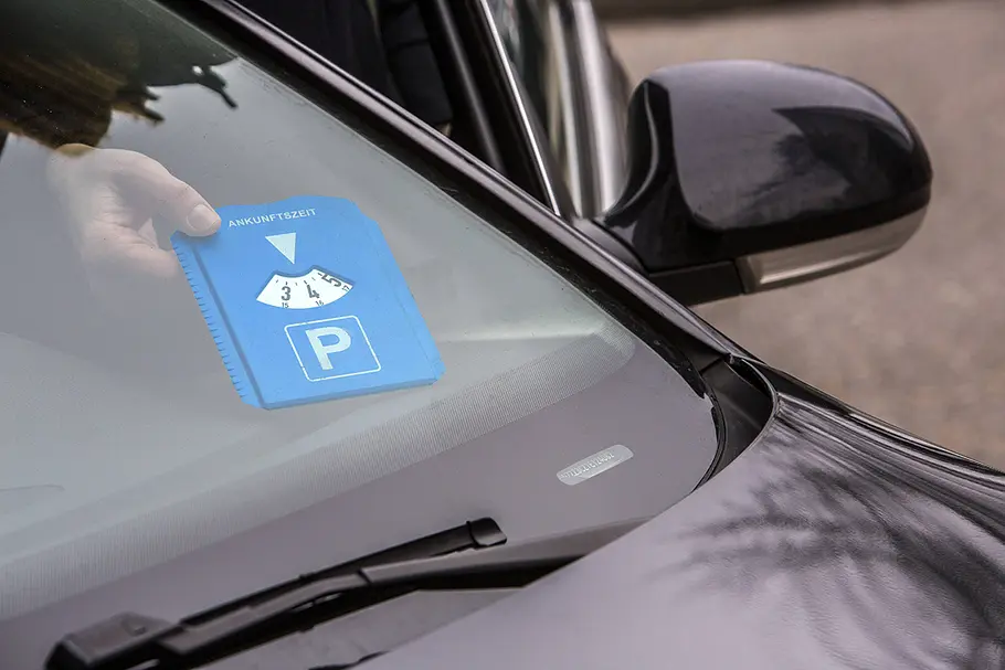 Elektronische Parkscheibe Needit Park Mini: Test Manuelle Parkscheibe hinter Windschutzscheibe mit Hand.