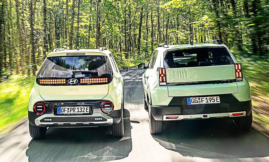 Hyundai Inster und Fiat Grande Panda fahrend nebeneinander von hinten.