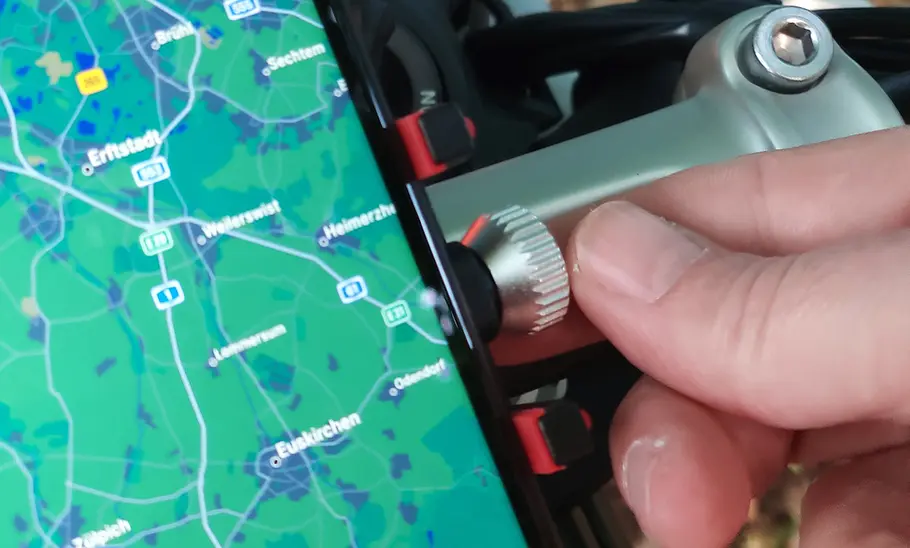 Rockbros Handyhalter fürs Motorrad mit Handy, Detailansicht des Rändelrads mit Hand eines Testers.