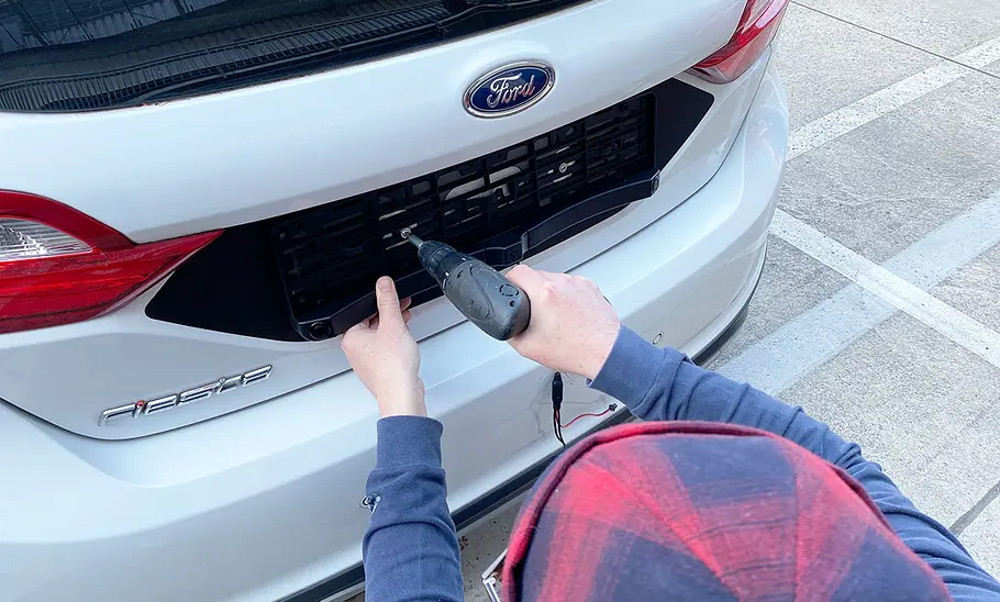 Tester beim Befestigen der Renkforce SB505 an einem Ford Fiesta auf einem Parkplatz.