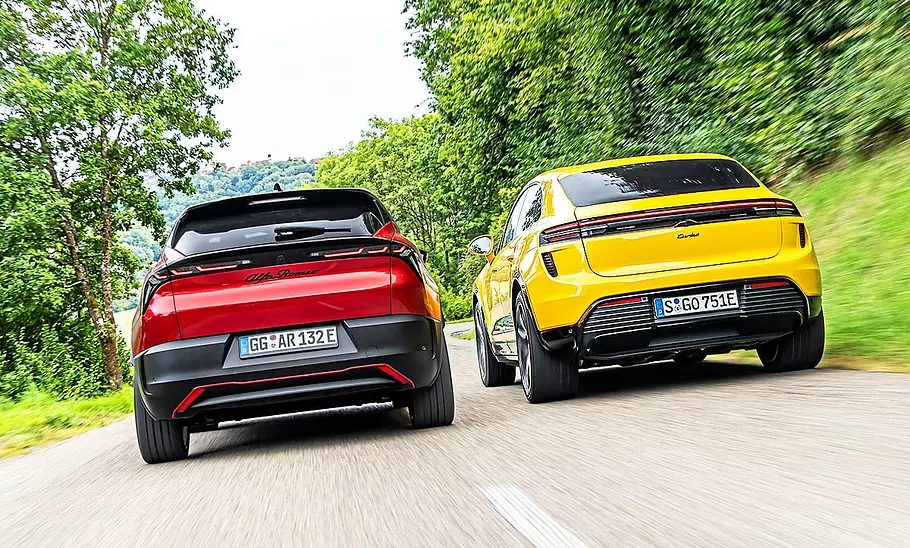 Der Alfa Romeo Junior Elettrica und Porsche Macan Turbo fahrend nebeneinander.