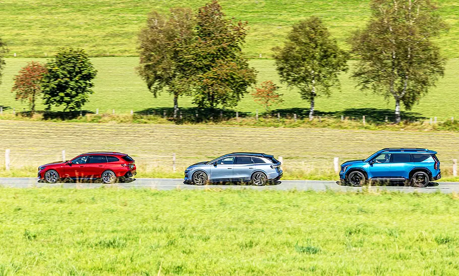 Der BMW i5 Touring, der VW ID.7 Tourer und der Kia E9 auf der Landstraße, von der Seite fotografiert.