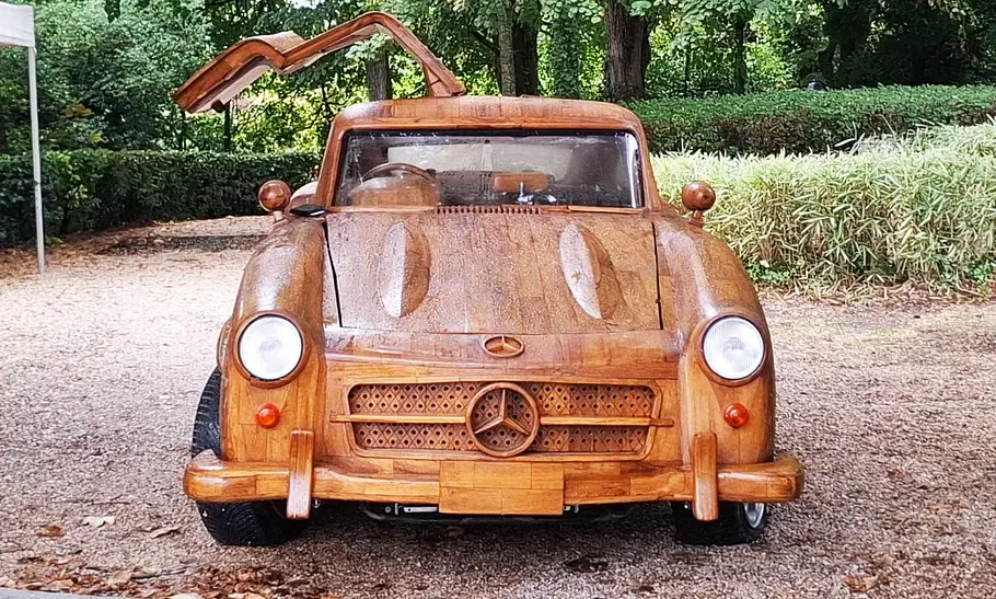 Mercedes Benz 300 SL aus Holz Der Mercedes Benz 300 SL aus Holz steht auf einem Schotterplatz und wurde von hinten schräg fotografiert.
