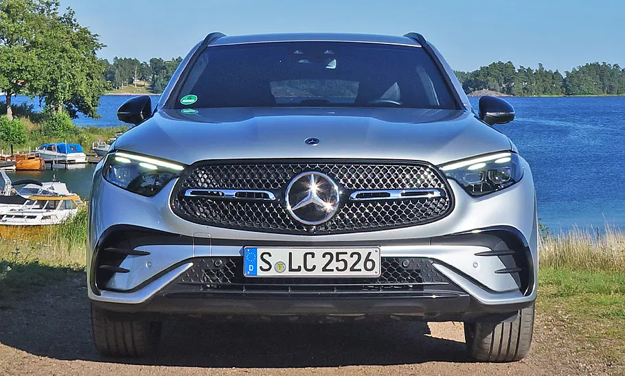 Mercedes GLC Der Mercedes GLC 300 d 4Matic steht auf einer Straße, im Hintergrund ein See. Fahrzeug frontal fotografiert.