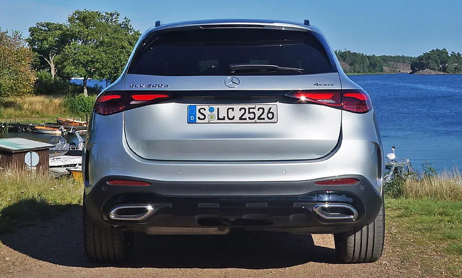 Mercedes GLC Der Mercedes GLC 300 d 4Matic steht auf einer Straße, im Hintergrund ein See. Fahrzeug von hinten fotografiert.