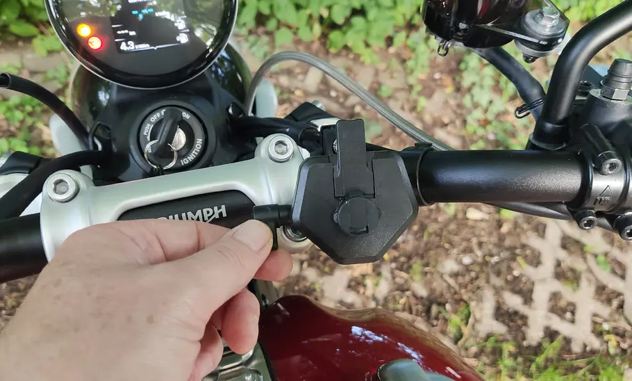 Detailansicht des Turnaroundtech Handyhalters fürs Motorrad im Test, am Lenker fotografiert mit Hand eines Testers.
