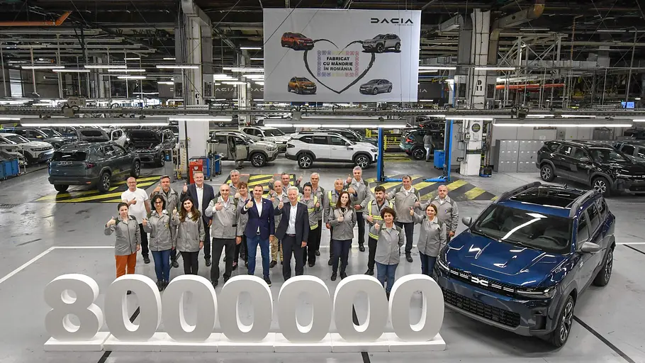 60 Jahre Dacia News Die Belegschaft im Dacia-Stammwerks Mioveni feiert am 25. April 2025 das 8.000.000. aus dem rumänischen Werk, einen dunkelblauen Dacia Bigster. Vor dem Auto und der Belegschaft steht eine Skulptur der Zahl 8.000.000, über der Produktionslinie hängt ein Banner zur Feier der Dacia-Produktion in Rumänien.