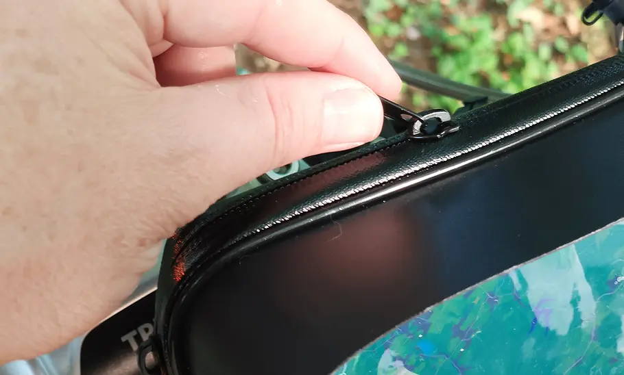 Detailansicht des Turnaroundtech Handyhalters fürs Motorrad im Test, mit Reißverschluss und Hand eines Testers.