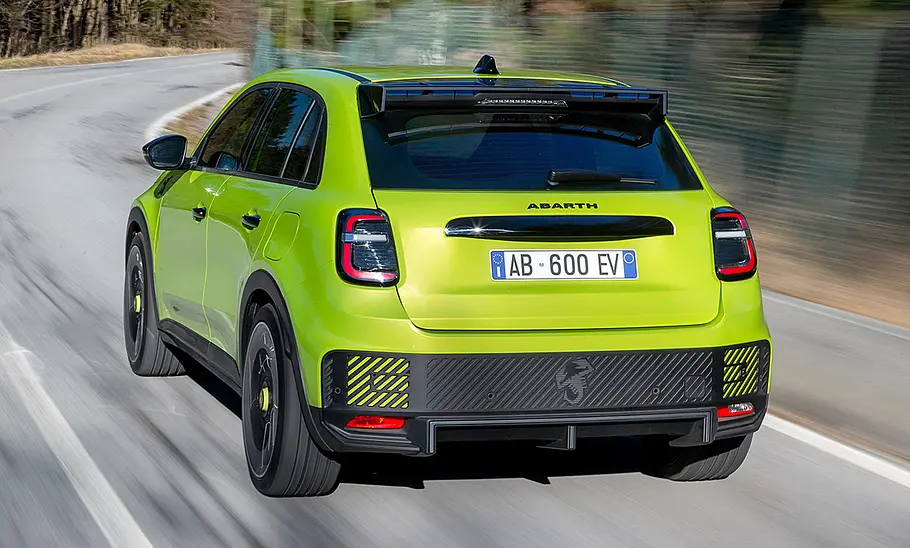 Der Abarth 600e (2024) fahrend von schräg hinten fotografiert.