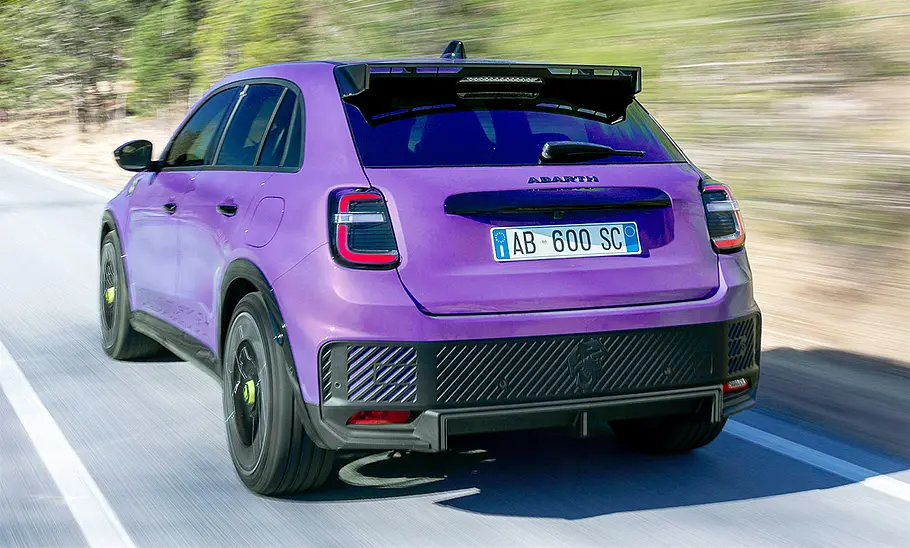 Der Abarth 600e (2024) fahrend von schräg hinten fotografiert.