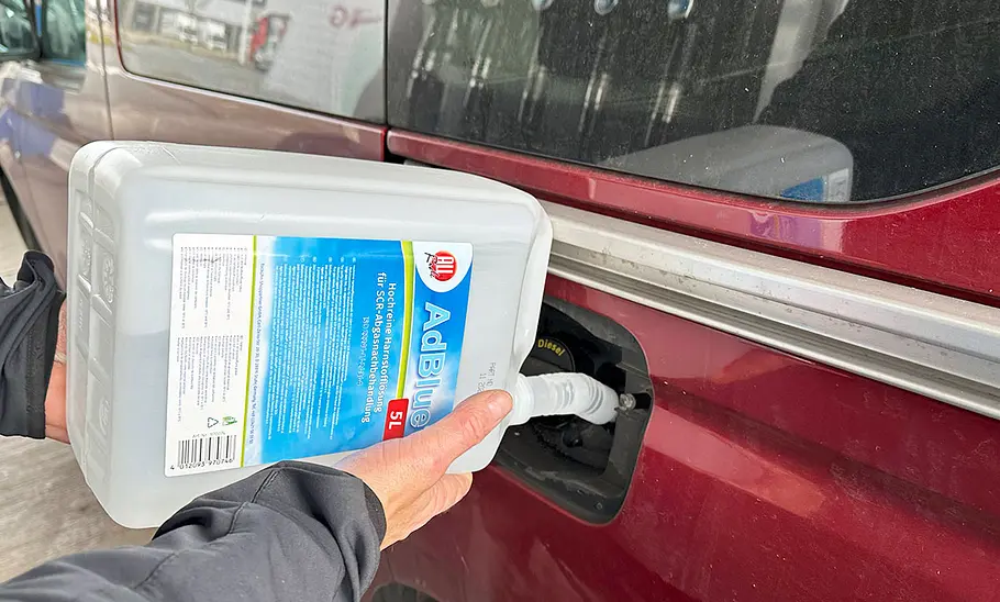 Person beim Befüllen des Adblue-Tanks eines Autos