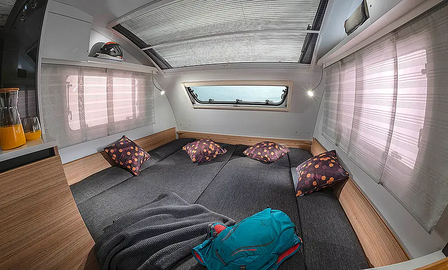 Der Wohnraum des Adria Action 361 LH (2024), umgebaut zum Bett, fotografiert aus der rechten hinteren Ecke heraus.