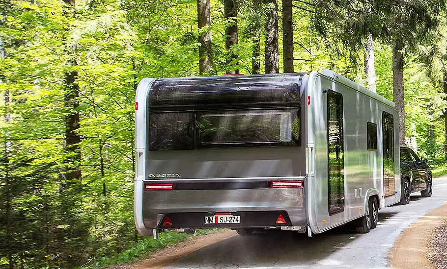 Der Adria Astella 904 HP (2026) von schräg hinten am Haken eines Zugfahrzeugs.