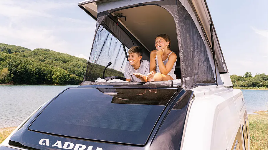 Die Außenansicht zeigt zwei Kinder auf dem Dach des Adria Twin Sports.