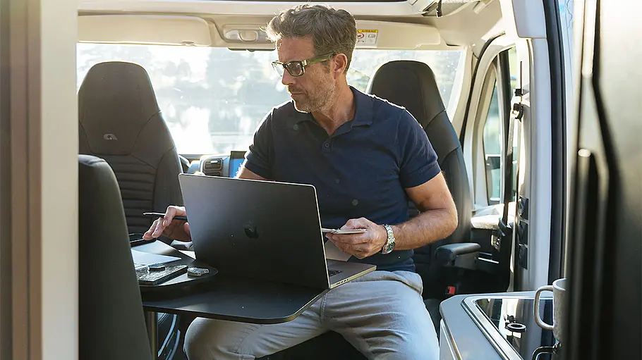 Die Innenansicht zeigt einen Mann mit Laptop im Innenraum des Adria Twin Supreme.