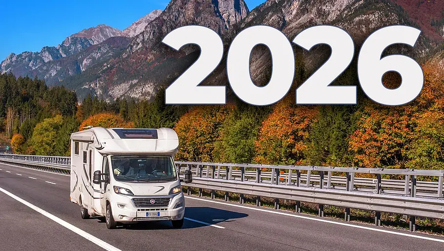 Das Bild zeigt ein Wohnmobil auf einer Autobahn in Tirol. Im Hintergrund sind Berge und Bäume mit herbstlichem Laub zu sehen.