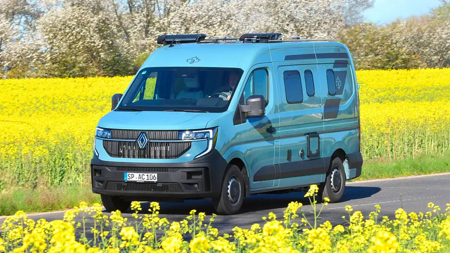 Der Ahorn Camp CV 560 fahrend von schräg vorne links auf einer Landstraße zwischen blühenden Rapsfeldern.