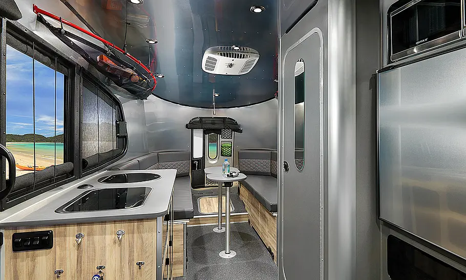 Das Bild zeigt den Wohnraum des Airstream Basecamp 20 (2025) mit Blick aus dem Bug in Richtung Heck.