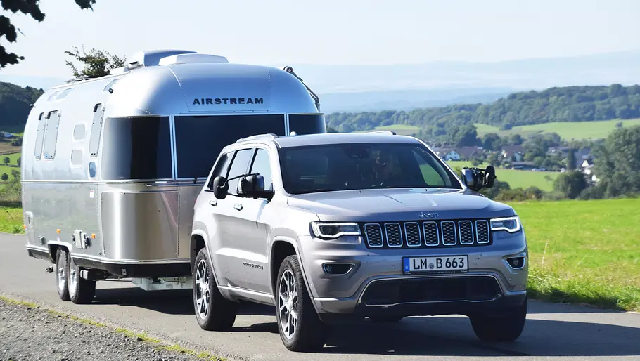 Airstream International 25 IB (2025) Die Außenaufnahme zeigt den Airstream International 25 IB am Haken eines Geländewagens als Zugfahrzeug.