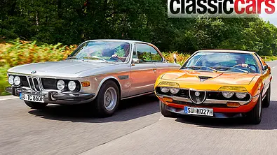 BMW 3.0 CSi und Alfa Romeo Montreal fahren nebeneinander her auf einer Landstraße, von schräg vorne fotografiert. - Foto: Wim Woeber