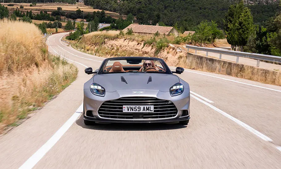 Der Aston Martin Vanquish Volante fahrend von vorne. Das Verdeck ist offen.