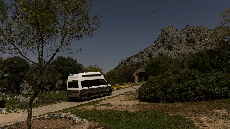 Der VW Grand California statisch von schräg hinten rechts bei Nacht.